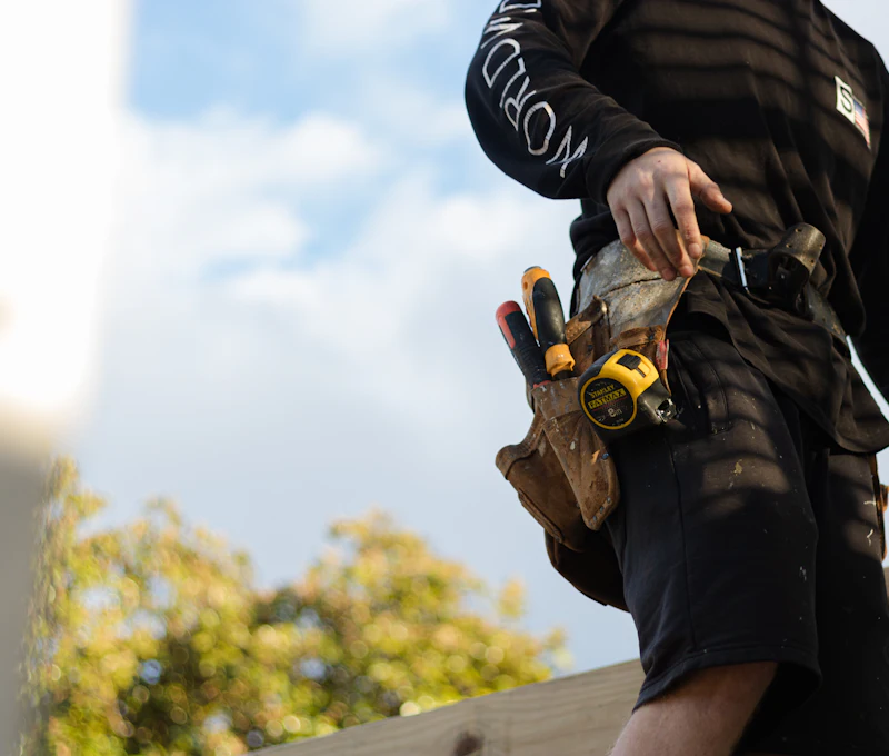 Handyman wearing a tool belt on a job outside a house