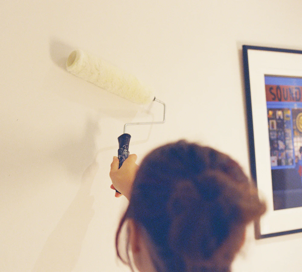 Painter rolling a fresh coat on a pale living room wall